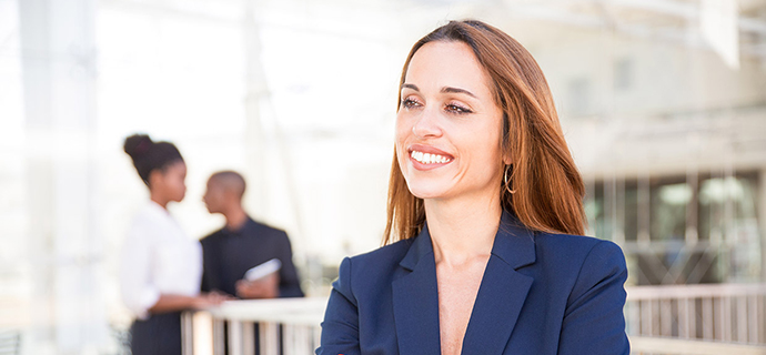 Portrait of happy businesswoman and her employees in background